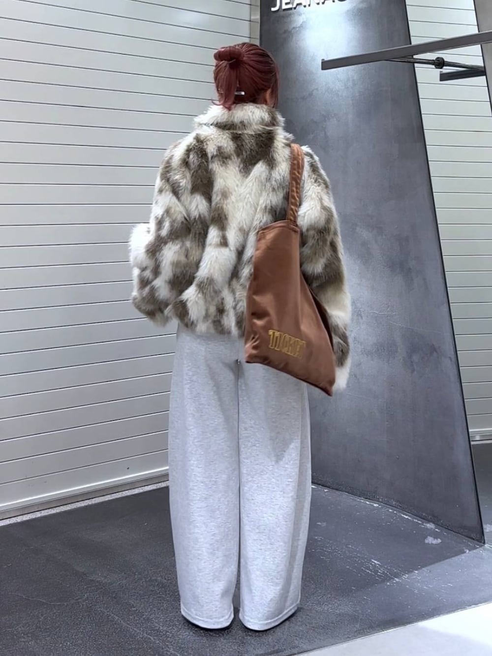 グレー系のブルゾン、ブラウン系のトートバッグ、グレー系のスウェットパンツを着用したレディースの秋コーディネートの5枚目の写真