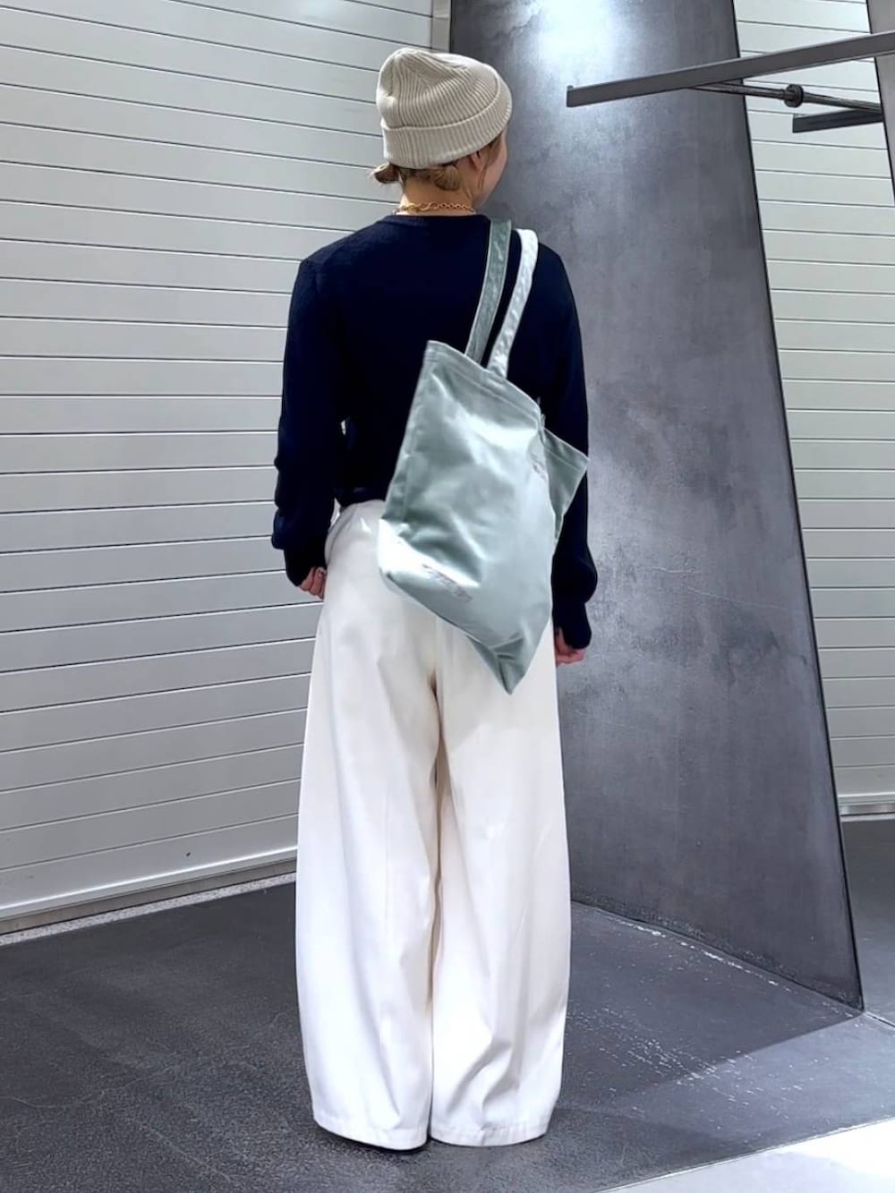 グリーン系のトートバッグ、ブラック系のパンプス、ホワイト系のスラックスを着用したレディースの秋コーディネートの5枚目の写真