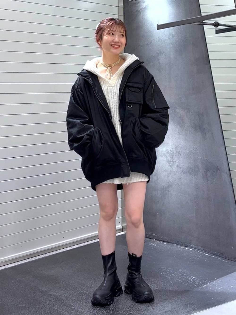 ブラック系のブーツ、ブラック系のブルゾン、ホワイト系のパーカーを着用したレディースの冬コーディネートの2枚目の写真