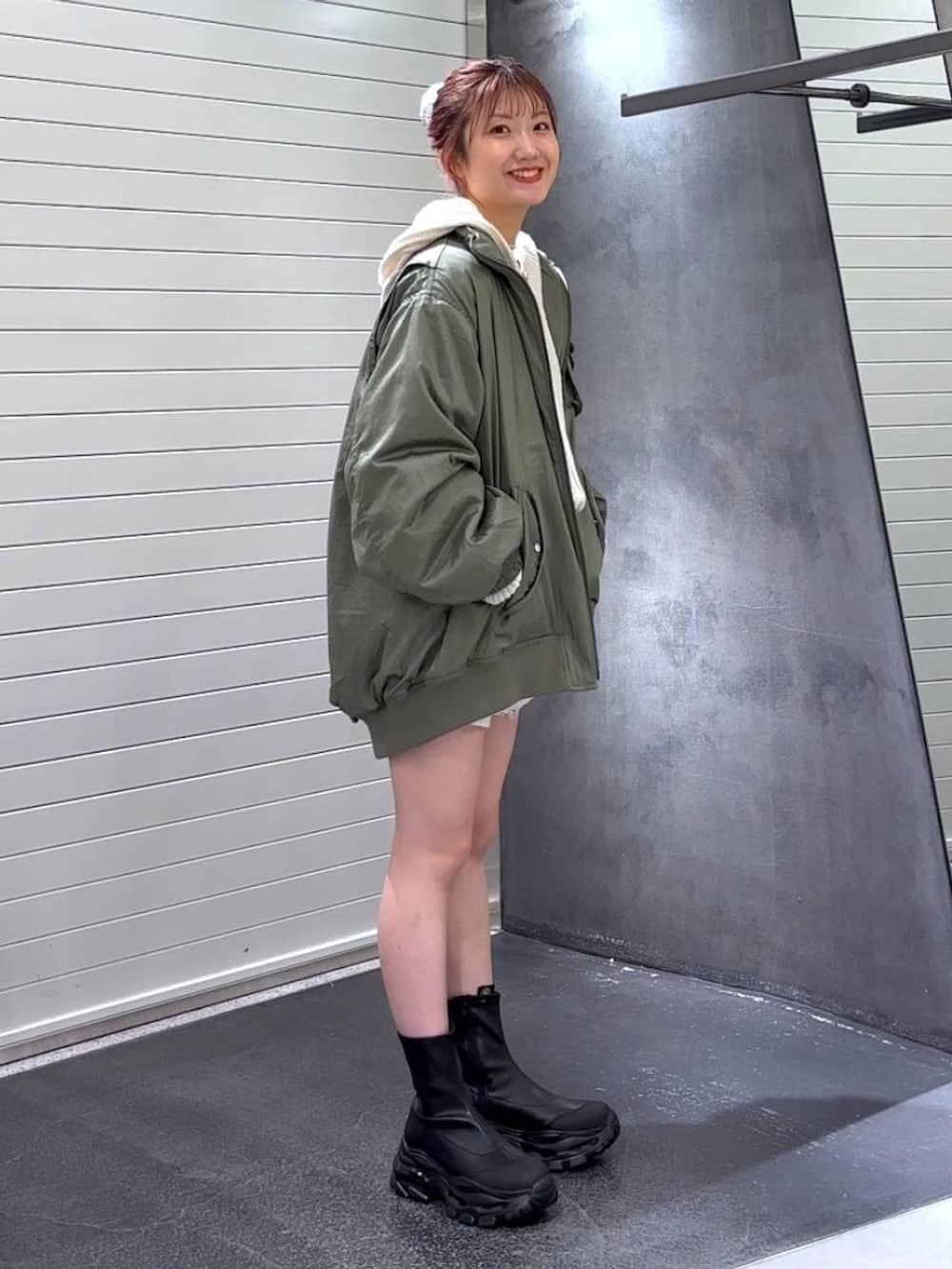 ブラック系のブーツ、グリーン系のブルゾン、ホワイト系のパーカーを着用したレディースの秋コーディネートの4枚目の写真