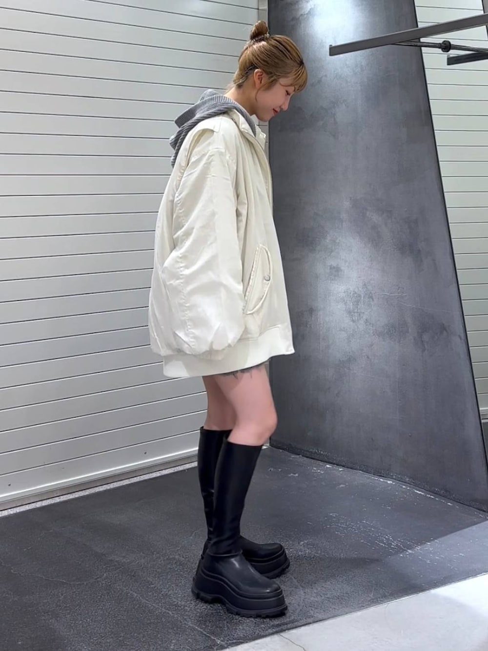 ホワイト系のブルゾン、ブラック系のブーツ、ホワイト系のタンクトップを着用したレディースの秋コーディネートの4枚目の写真