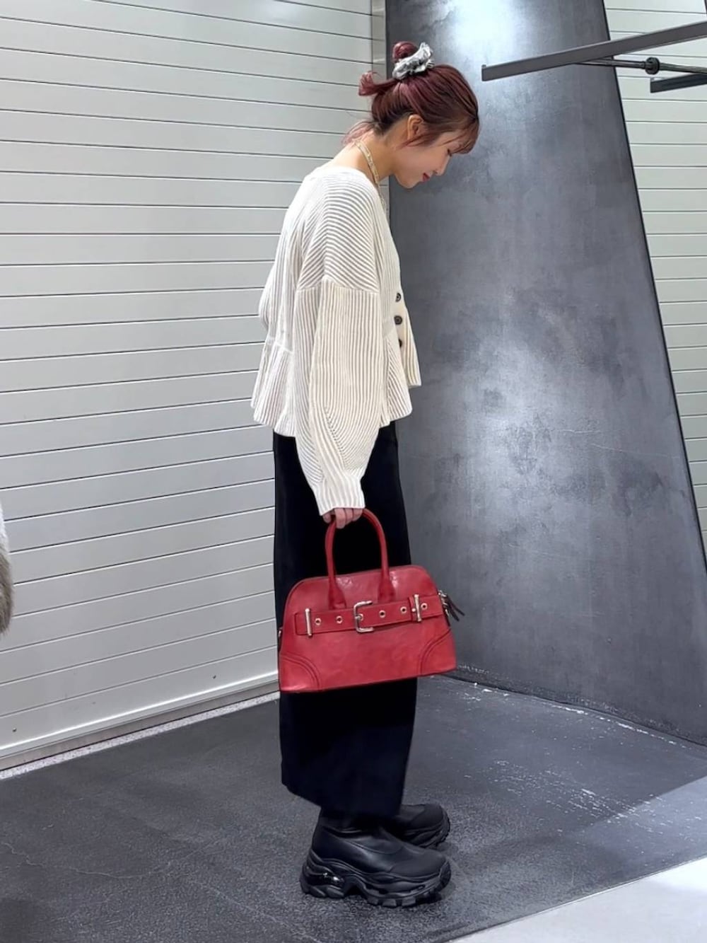 ブラック系のスカート、ブラック系のブーツ、レッド系のボストンバッグを着用したレディースの秋コーディネートの4枚目の写真
