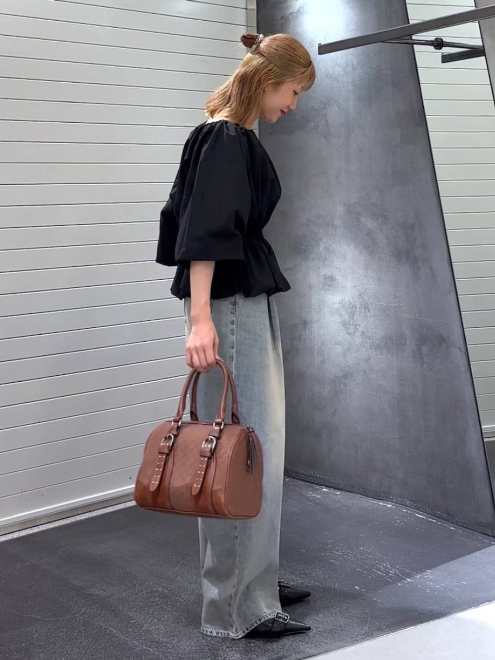 ブルー系のデニムパンツ、ブラック系のパンプス、レッド系のボストンバッグを着用したレディースの秋コーディネートの4枚目の写真