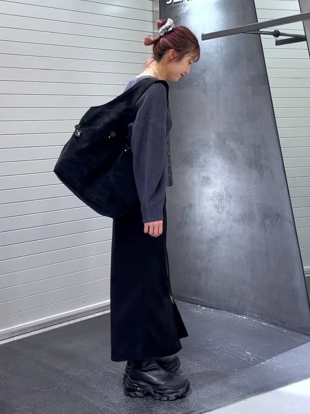 ブラック系のスカート、ブラック系のブーツ、ブラック系のトートバッグを着用したレディースの秋コーディネートの4枚目の写真