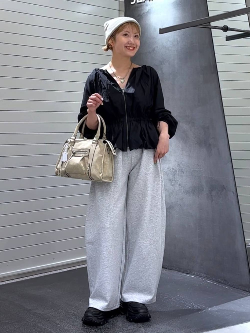 ベージュ系のボストンバッグ、グレー系のスウェットパンツ、ブラック系のローファーを着用したレディースの秋コーディネートの2枚目の写真