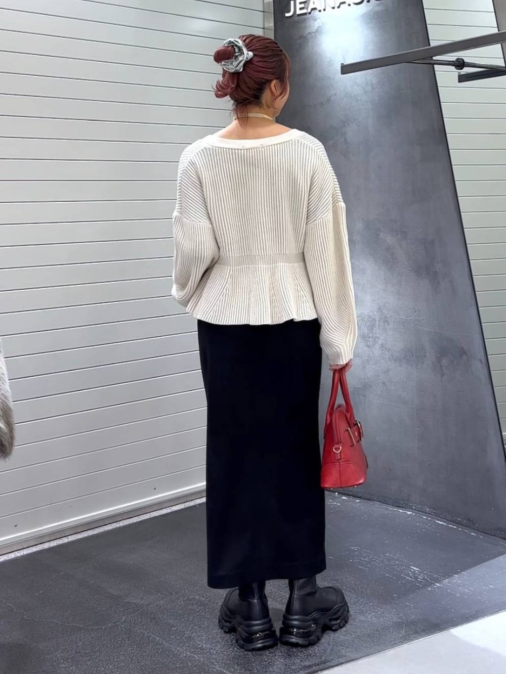 ブラック系のスカート、ブラック系のブーツ、レッド系のボストンバッグを着用したレディースの秋コーディネートの5枚目の写真