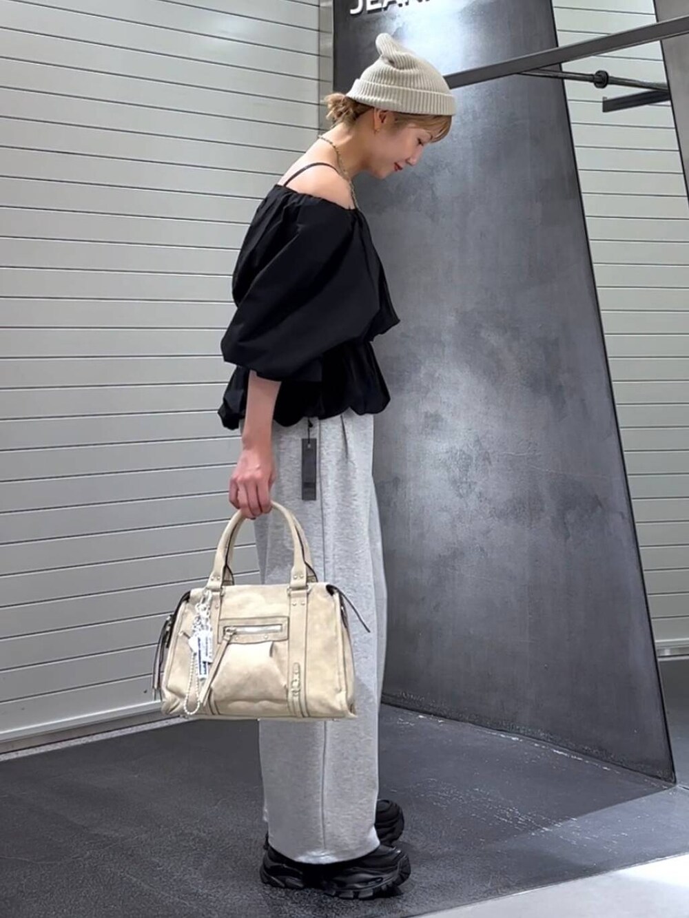 ベージュ系のボストンバッグ、ブラック系のローファー、グレー系のスウェットパンツを着用したレディースの秋コーディネートの4枚目の写真