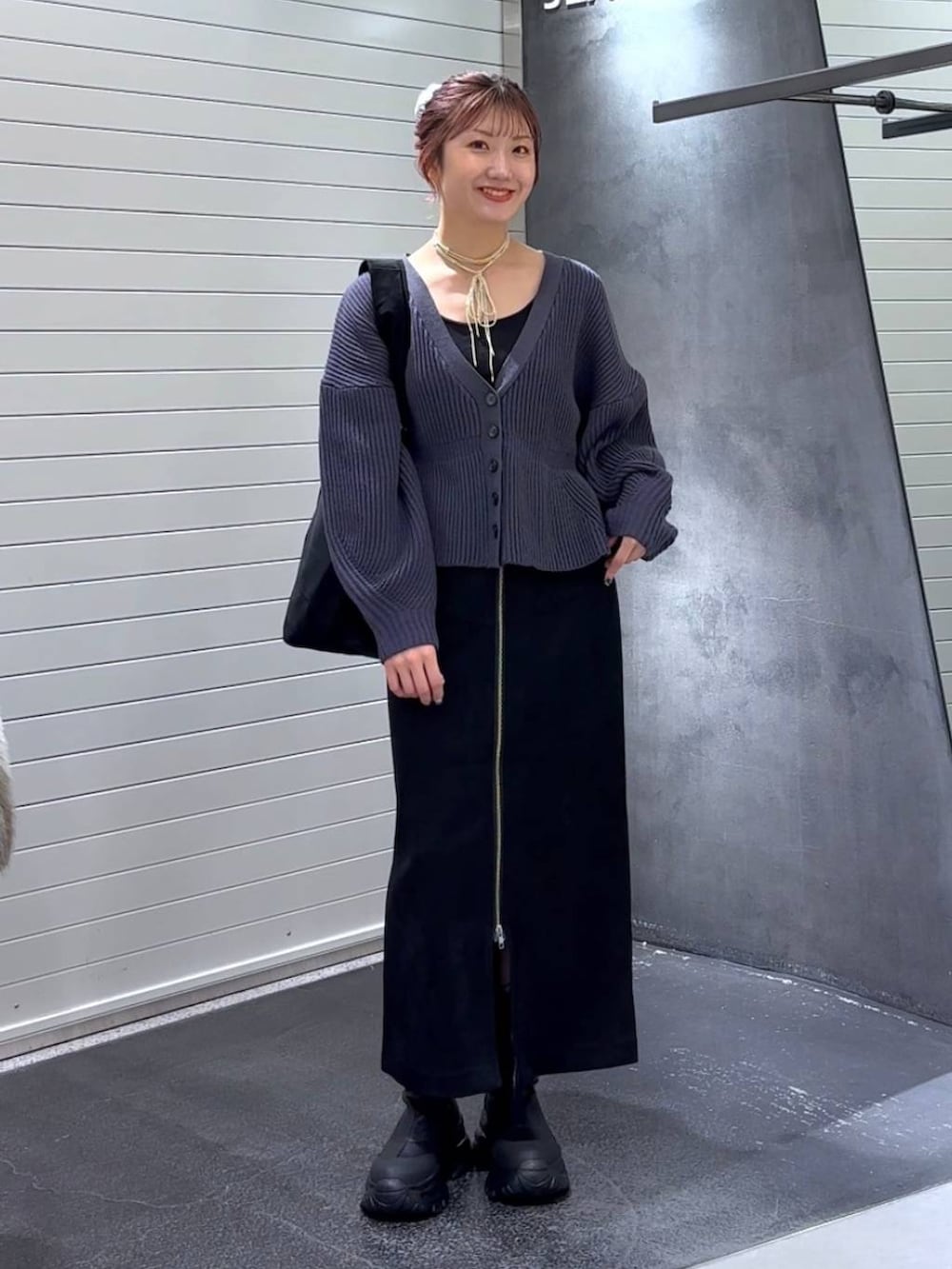 ブラック系のスカート、ブラック系のブーツ、ブラック系のトートバッグを着用したレディースの秋コーディネートの2枚目の写真