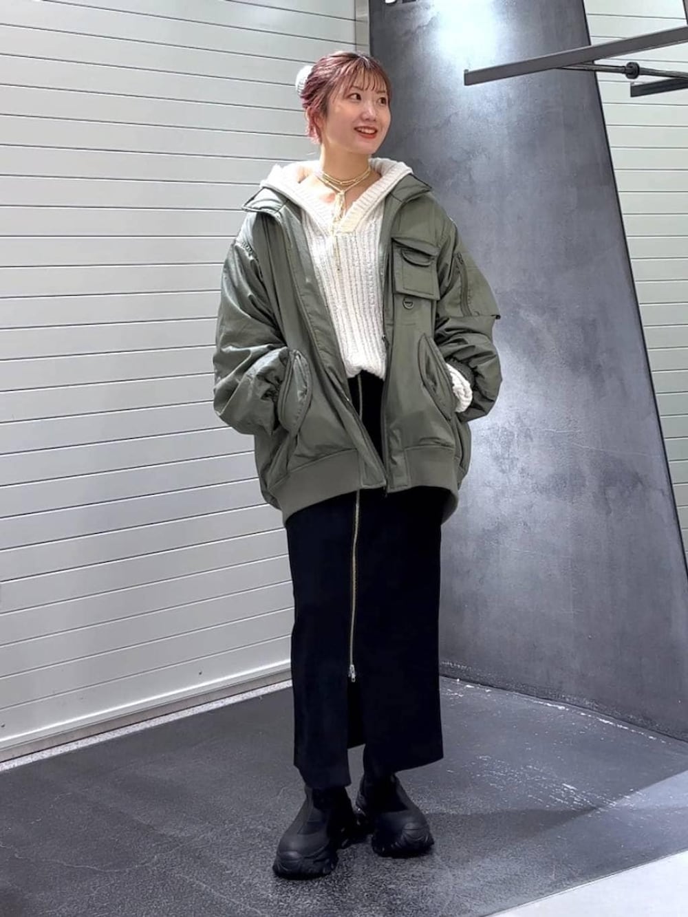 ブラック系のスカート、ブラック系のブーツ、グリーン系のブルゾンを着用したレディースの秋コーディネートの2枚目の写真