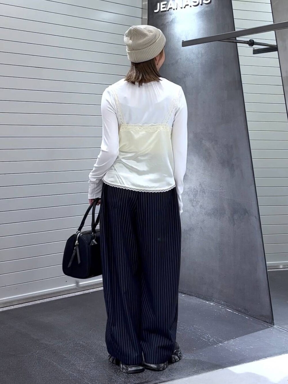 ホワイト系のTシャツ/カットソー、ブラック系のスニーカー、ブルー系のスラックスを着用したレディースの秋コーディネートの5枚目の写真