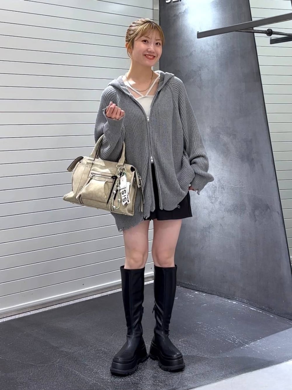 ベージュ系のボストンバッグ、ブラック系のブーツ、ホワイト系のタンクトップを着用したレディースの秋コーディネートの2枚目の写真