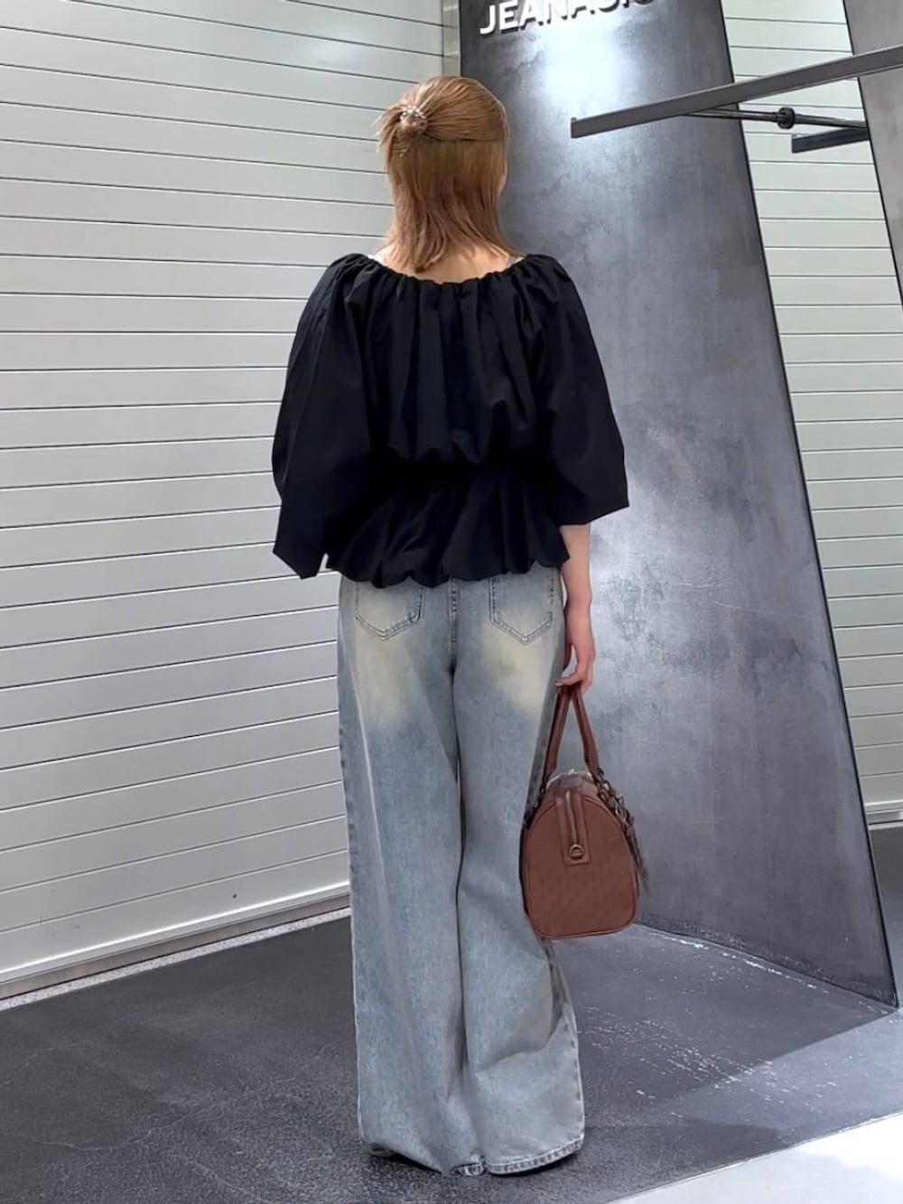 ブルー系のデニムパンツ、ブラック系のパンプス、レッド系のボストンバッグを着用したレディースの秋コーディネートの5枚目の写真