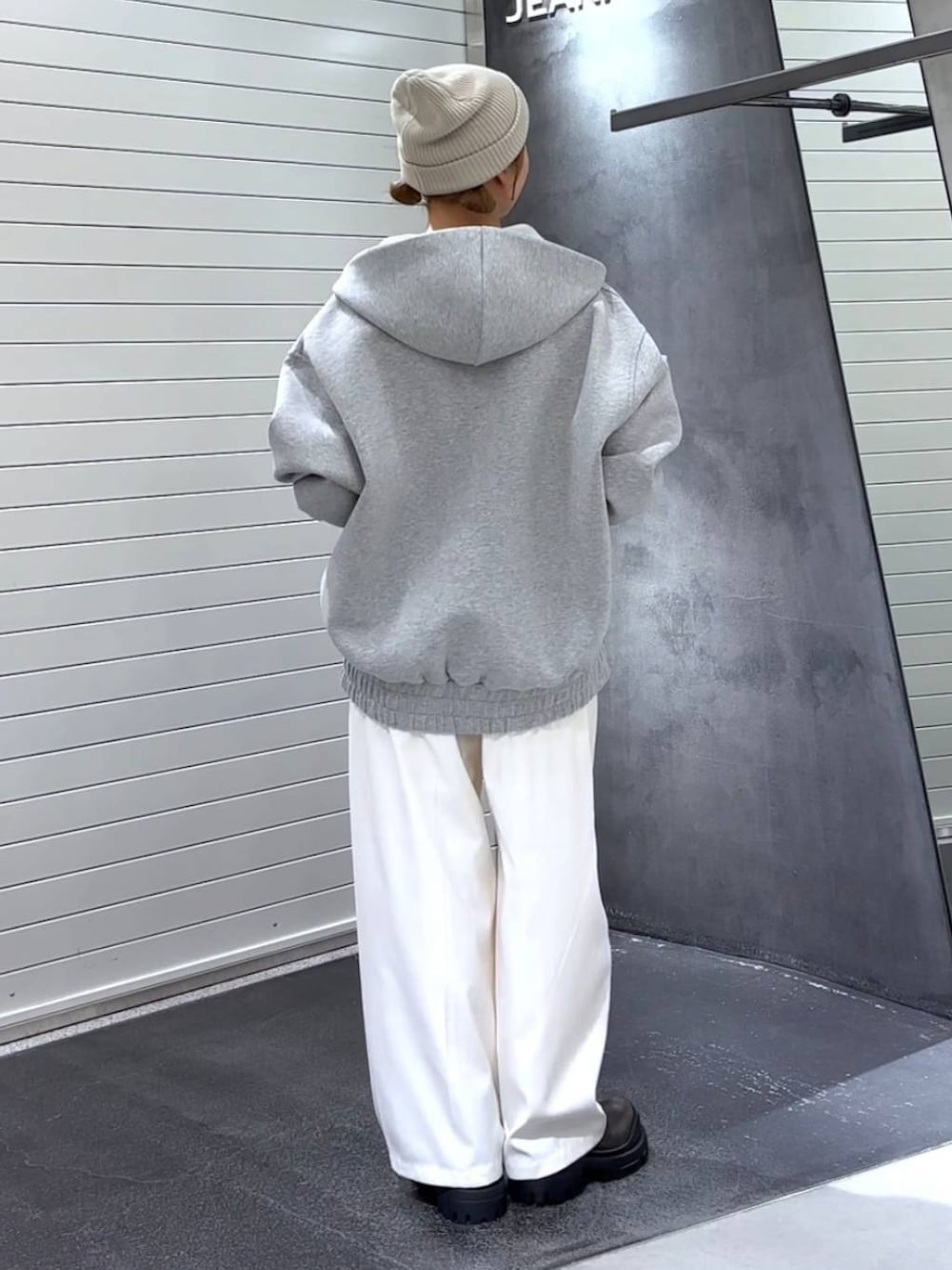 グレー系のパーカー、グリーン系のブーツ、ホワイト系のスラックスを着用したレディースの秋コーディネートの5枚目の写真