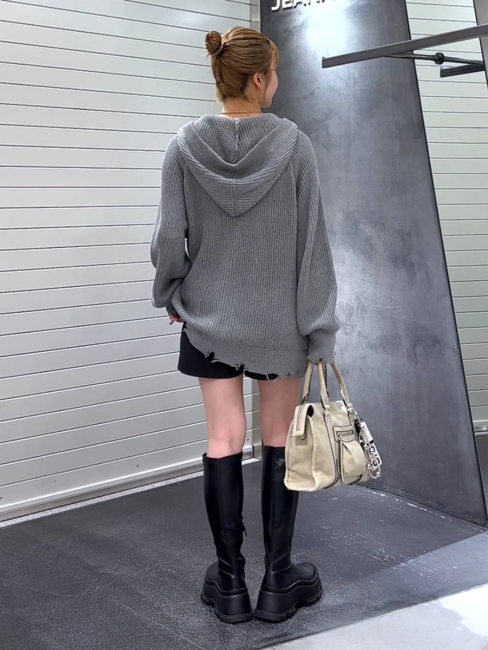 ベージュ系のボストンバッグ、ブラック系のブーツ、ホワイト系のタンクトップを着用したレディースの秋コーディネートの4枚目の写真