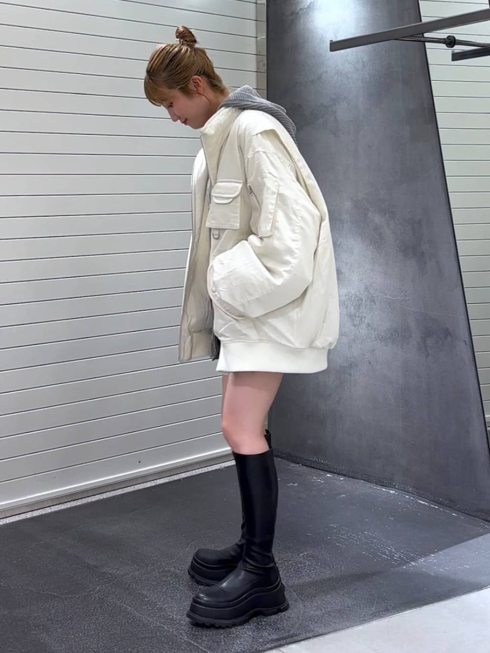 ホワイト系のブルゾン、ブラック系のブーツ、ホワイト系のタンクトップを着用したレディースの秋コーディネートの6枚目の写真