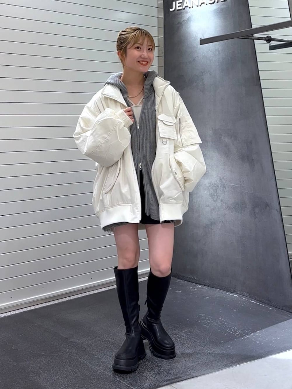 ホワイト系のブルゾン、ブラック系のブーツ、ホワイト系のタンクトップを着用したレディースの秋コーディネートの3枚目の写真