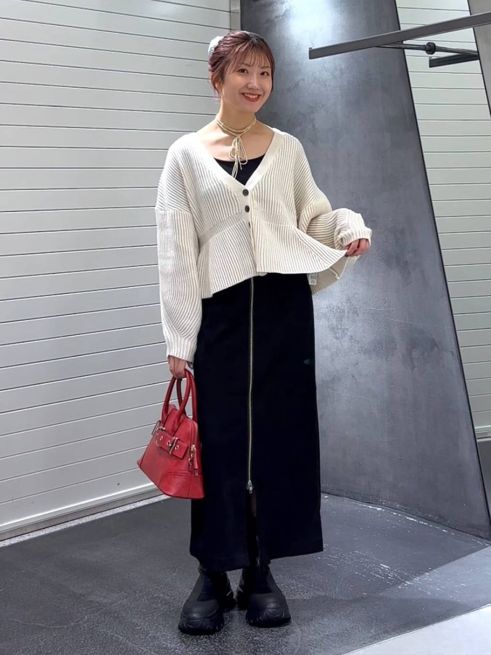 ブラック系のスカート、ブラック系のブーツ、レッド系のボストンバッグを着用したレディースの秋コーディネートの3枚目の写真