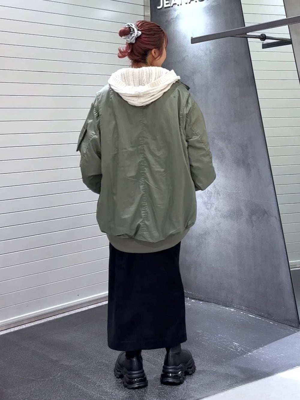 ブラック系のスカート、ブラック系のブーツ、グリーン系のブルゾンを着用したレディースの秋コーディネートの5枚目の写真