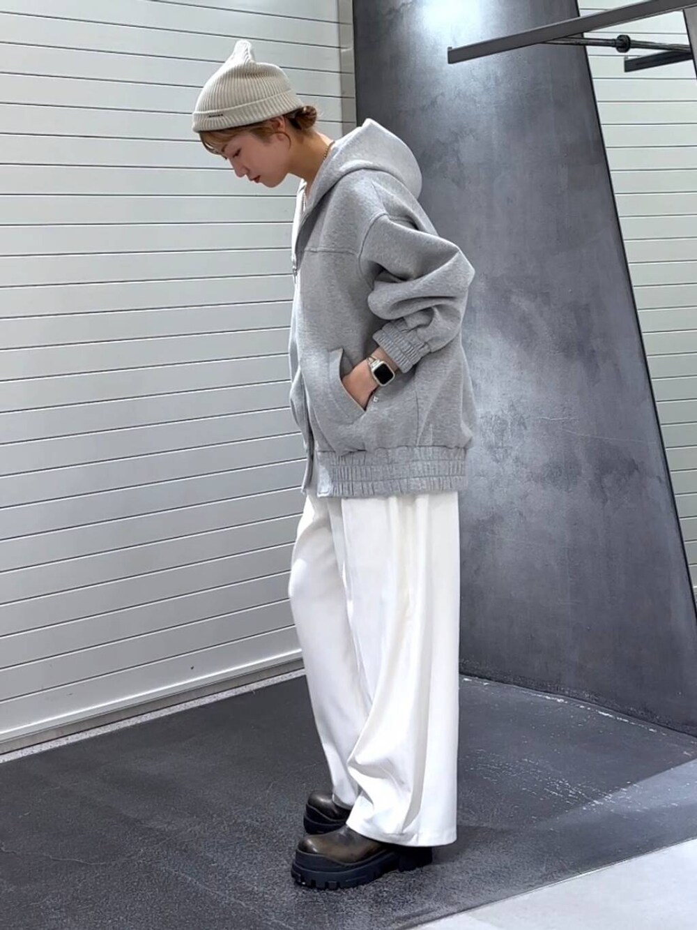 グレー系のパーカー、グリーン系のブーツ、ホワイト系のスラックスを着用したレディースの秋コーディネートの6枚目の写真