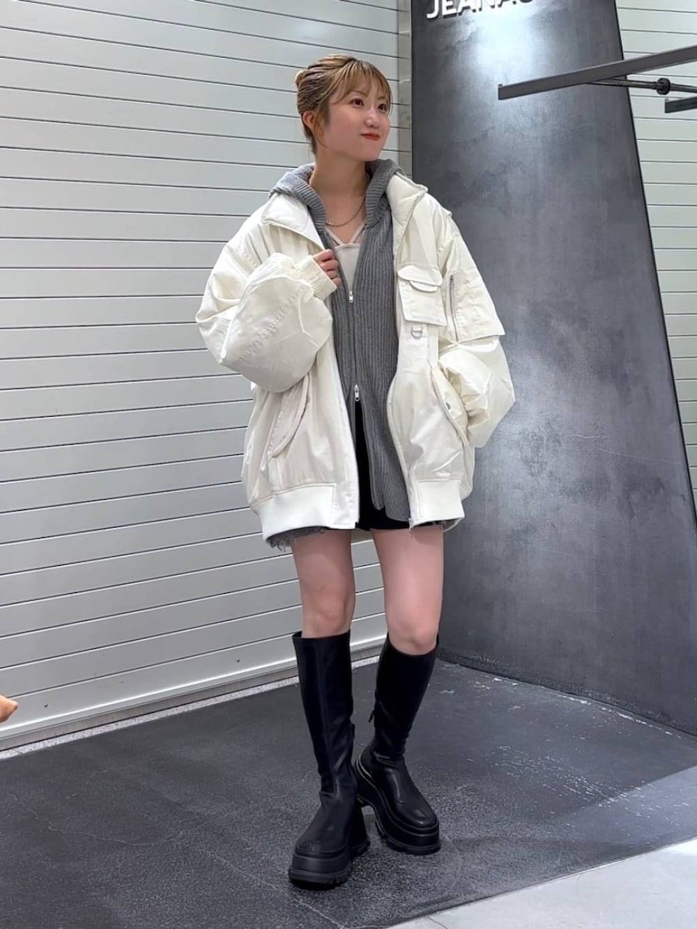 ホワイト系のブルゾン、ブラック系のブーツ、ホワイト系のタンクトップを着用したレディースの秋コーディネートの2枚目の写真
