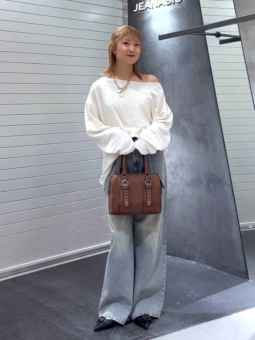 ブルー系のデニムパンツ、ブラック系のパンプス、レッド系のボストンバッグを着用したレディースの秋コーディネートの3枚目の写真