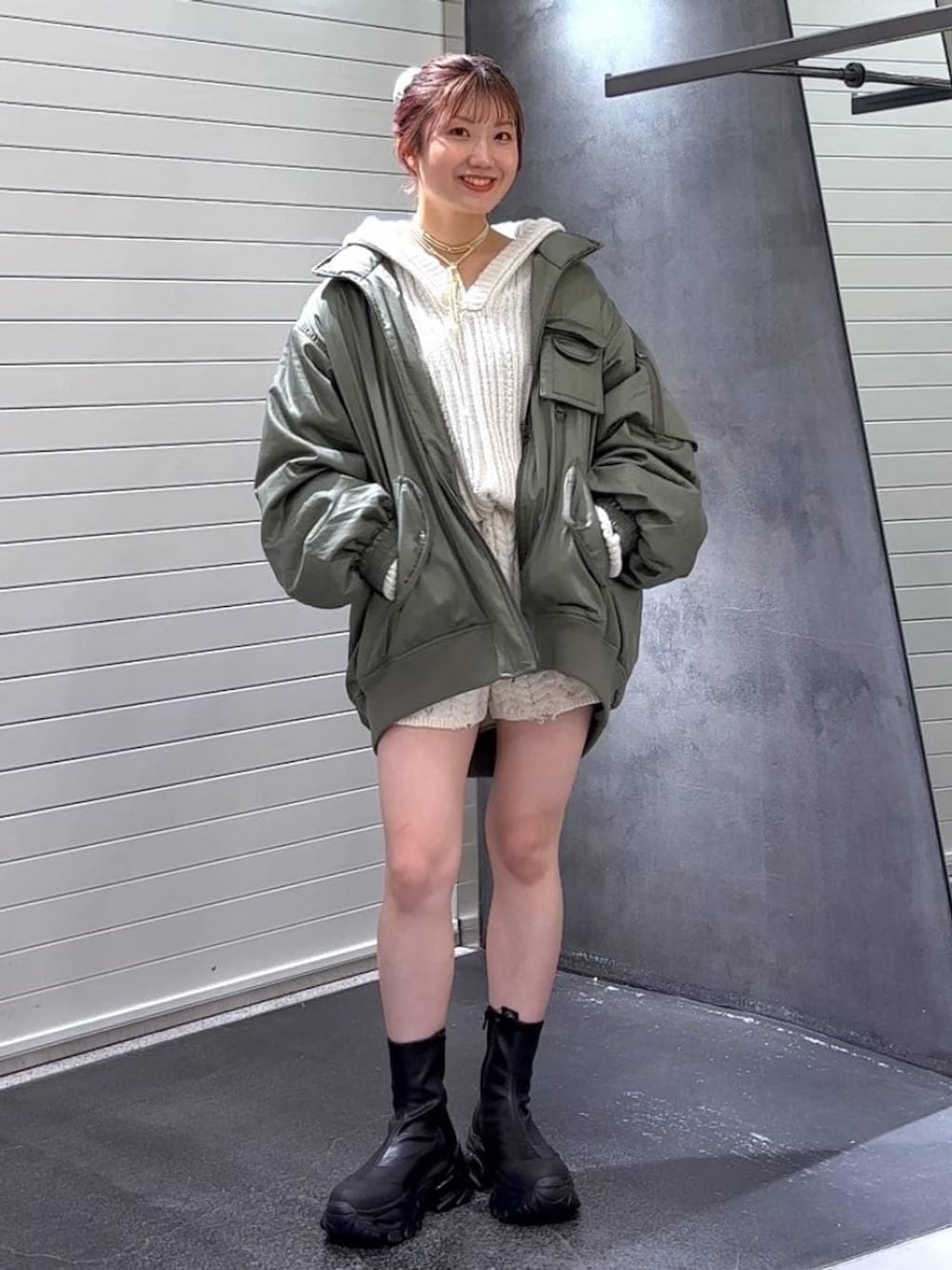 ブラック系のブーツ、グリーン系のブルゾン、ホワイト系のパーカーを着用したレディースの秋コーディネートの2枚目の写真