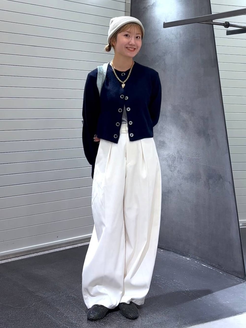 グリーン系のトートバッグ、ブラック系のパンプス、ホワイト系のスラックスを着用したレディースの秋コーディネートの3枚目の写真