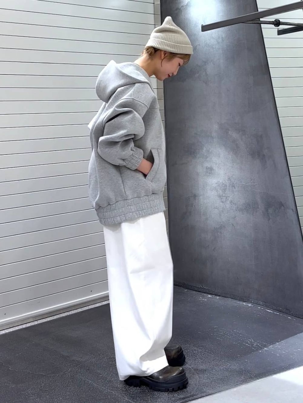 グレー系のパーカー、グリーン系のブーツ、ホワイト系のスラックスを着用したレディースの秋コーディネートの4枚目の写真