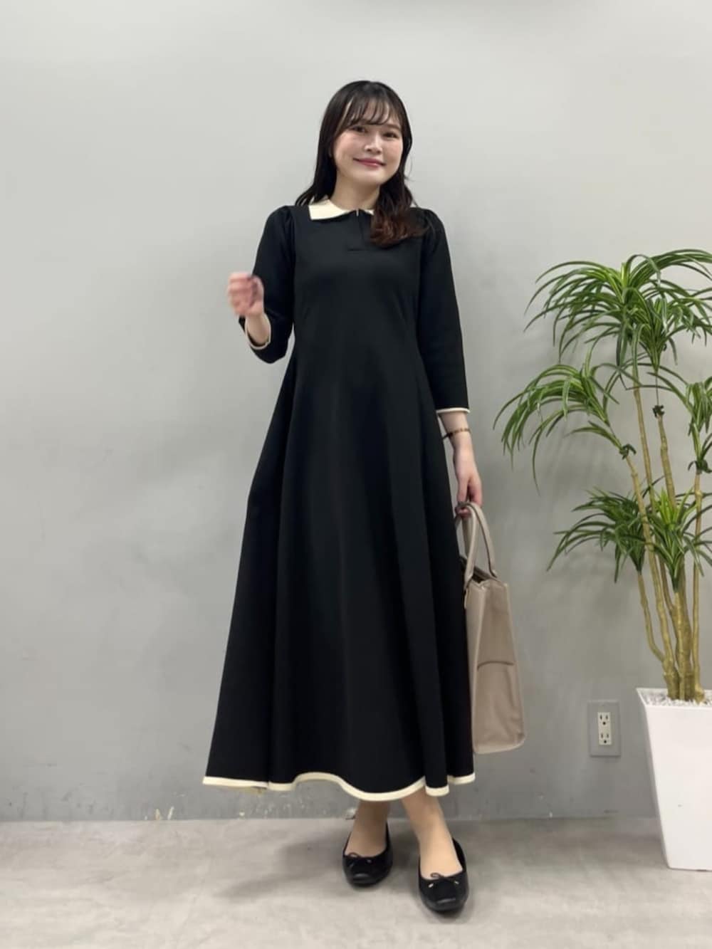 ベージュ系のショルダーバッグ、ブラック系のワンピースを着用したレディースの夏コーディネートの2枚目の写真