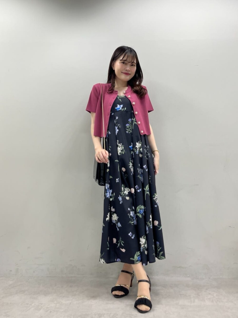 ブラック系のショルダーバッグ、ブラック系のワンピース、ピンク系のカーディガン/ボレロを着用したレディースの夏コーディネートの2枚目の写真