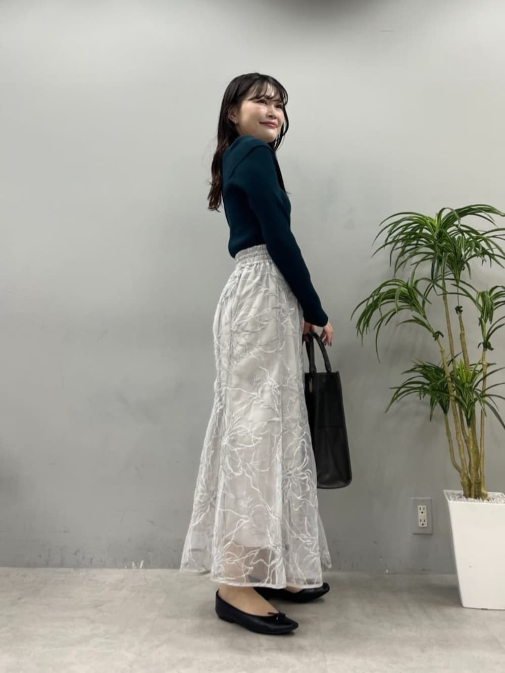 ブラック系のショルダーバッグ、グリーン系のニット/セーターを着用したレディースの夏コーディネートの4枚目の写真