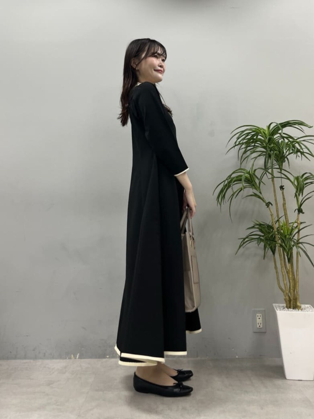 ベージュ系のショルダーバッグ、ブラック系のワンピースを着用したレディースの夏コーディネートの3枚目の写真