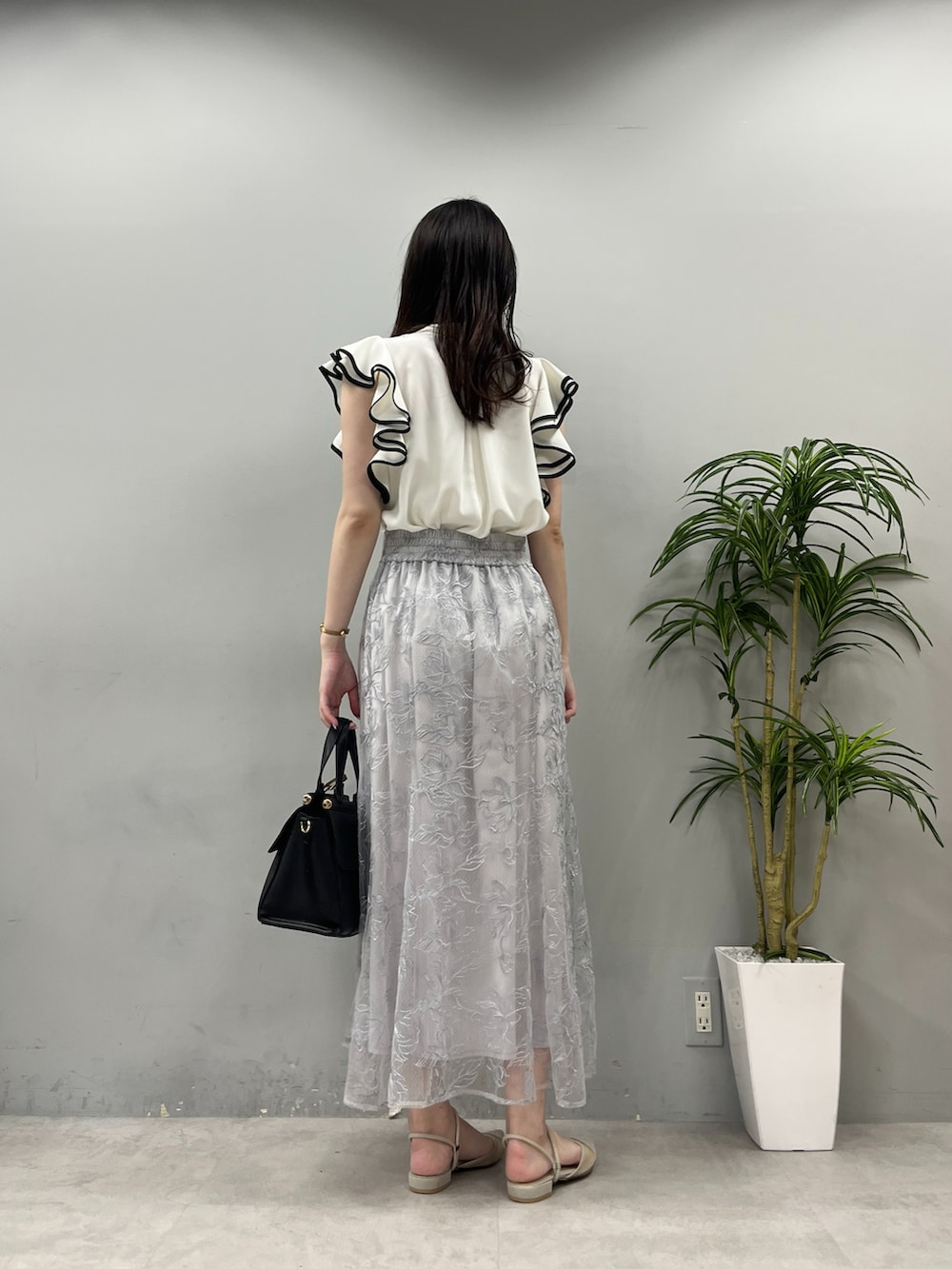 ブラック系のショルダーバッグ、ブルー系のスカート、ホワイト系のシャツ/ブラウスを着用したレディースの春コーディネートの3枚目の写真