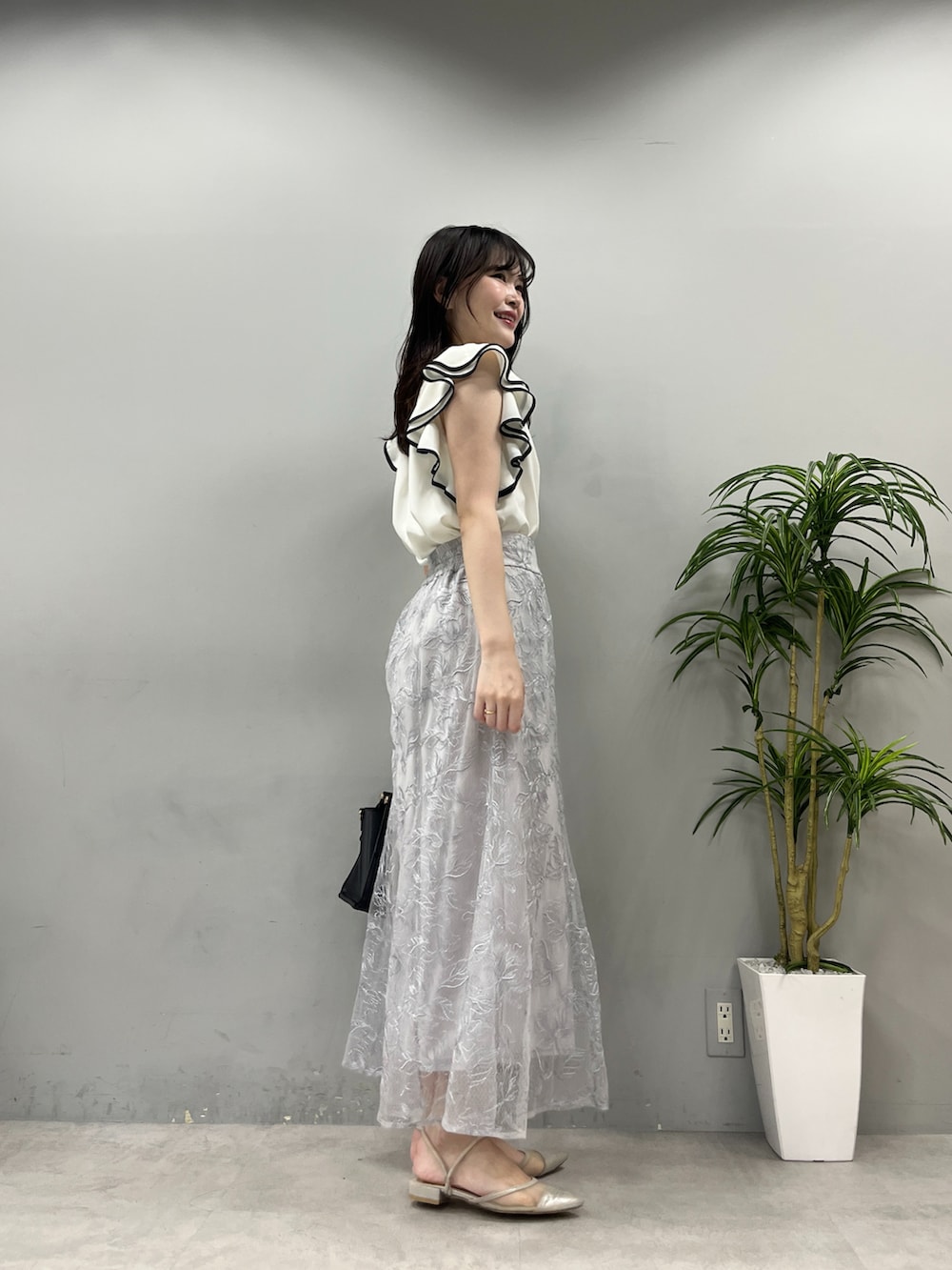 ブラック系のショルダーバッグ、ブルー系のスカート、ホワイト系のシャツ/ブラウスを着用したレディースの春コーディネートの2枚目の写真