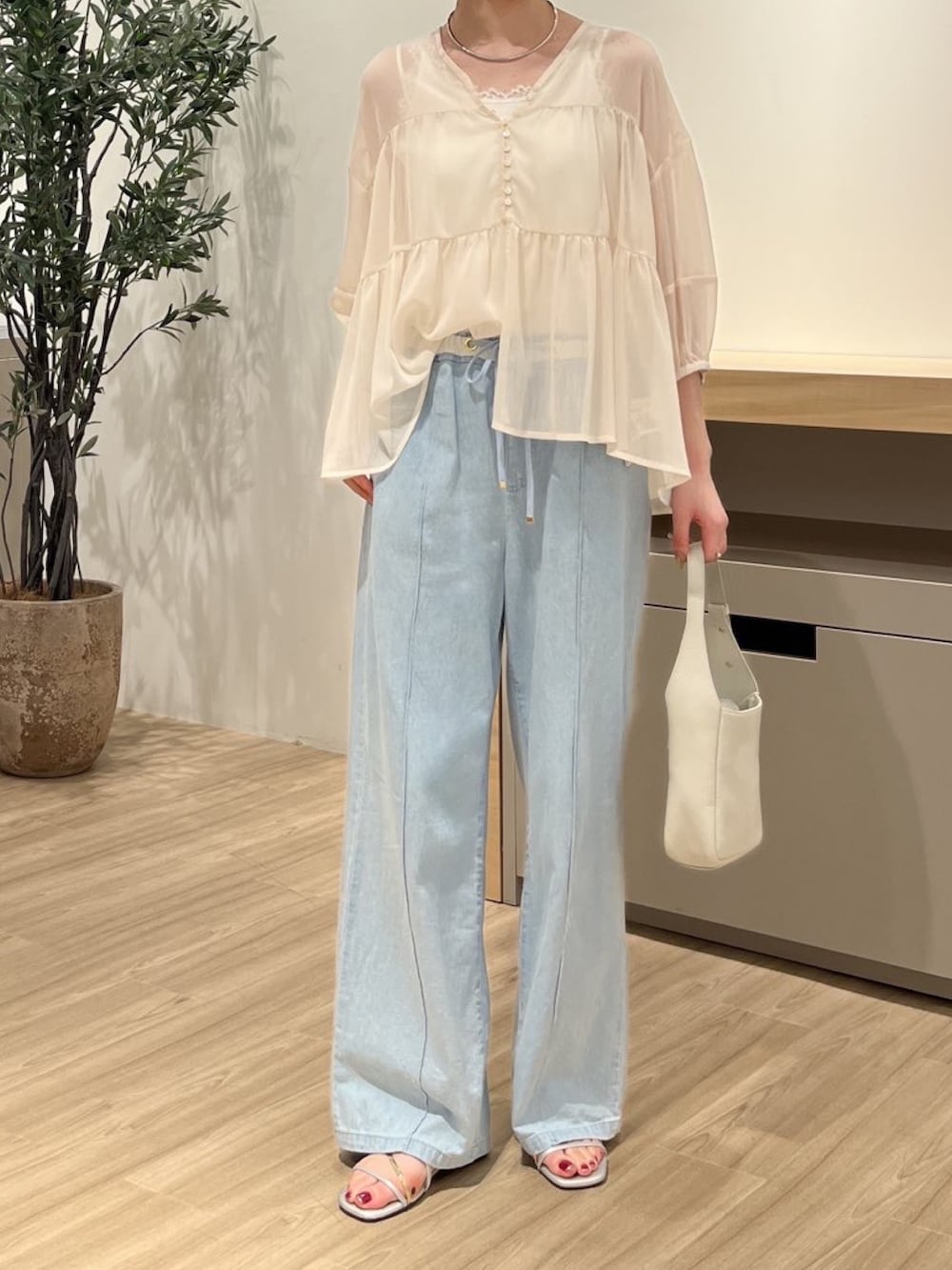ホワイト系のシャツ/ブラウス、ブルー系のデニムパンツ、シルバー系のサンダルを着用したレディースの夏コーディネートの2枚目の写真