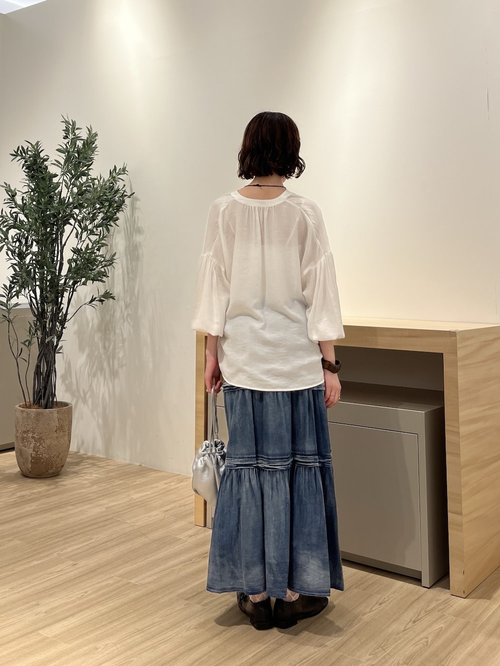 ホワイト系のシャツ/ブラウス、ブルー系のスカート、シルバー系のトートバッグを着用したレディースの夏コーディネートの3枚目の写真
