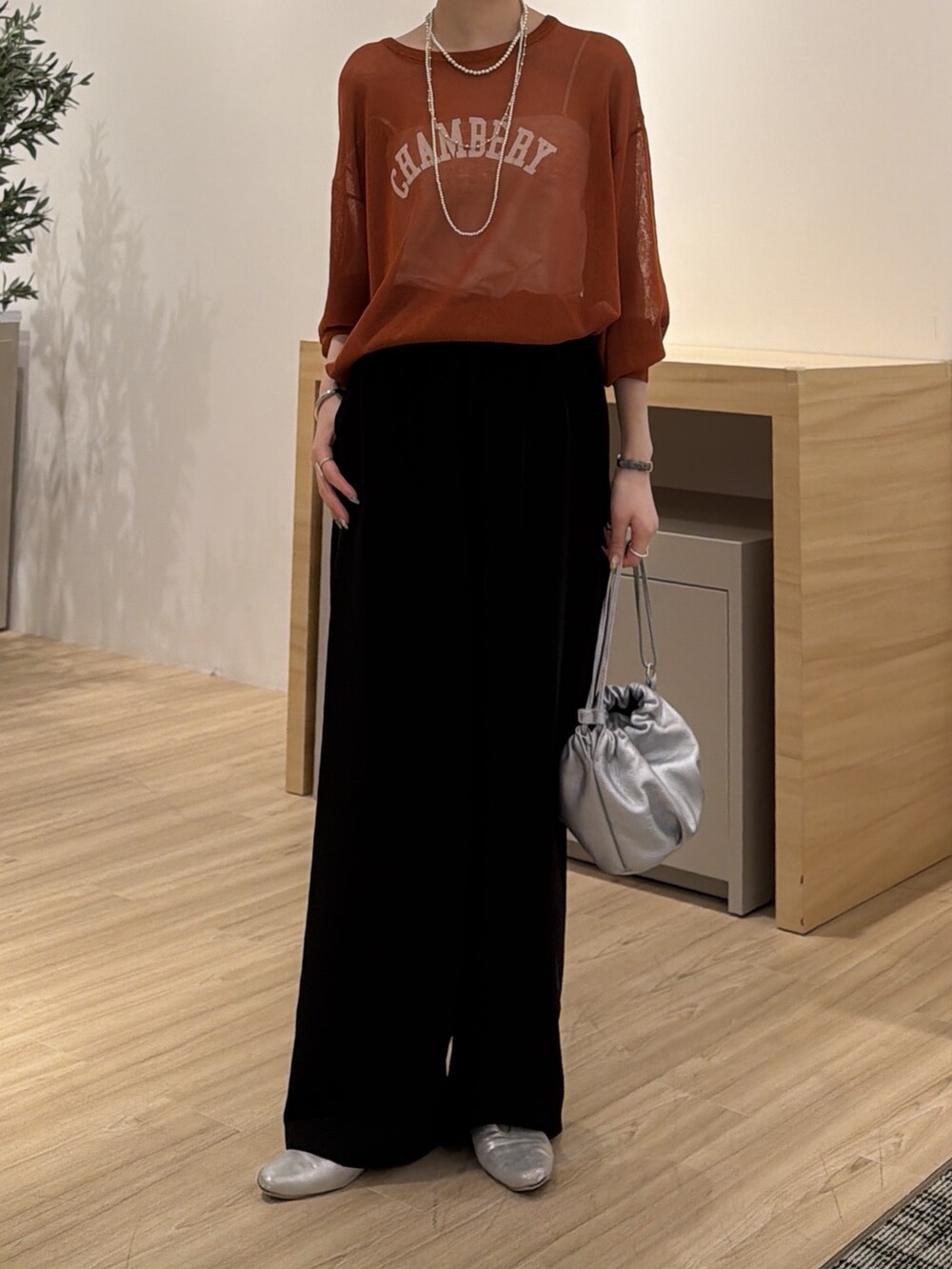 オレンジ系のニット/セーター、ブラック系のその他パンツ、シルバー系のトートバッグを着用したレディースの秋コーディネートの2枚目の写真