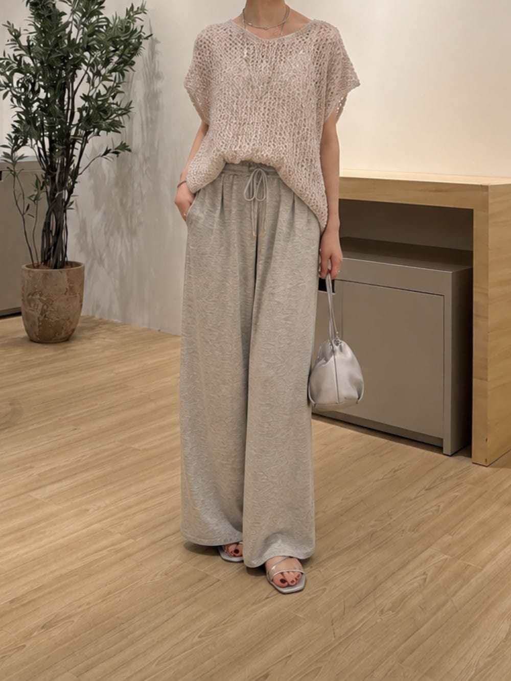 グレー系のニット/セーター、グレー系のその他パンツ、シルバー系のサンダルを着用したレディースの夏コーディネートの2枚目の写真