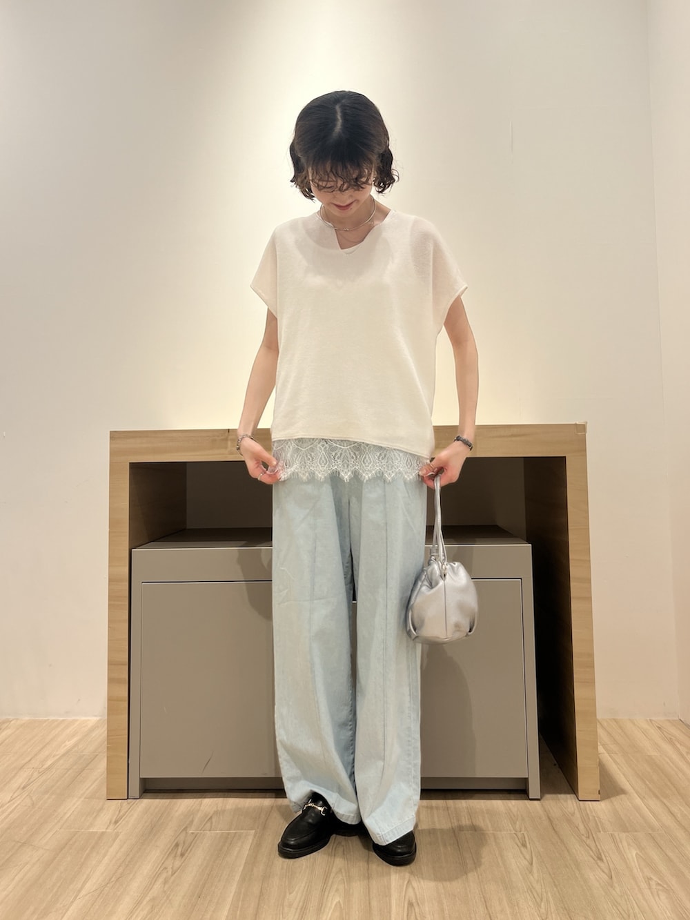 ホワイト系のニット/セーター、ブルー系のデニムパンツ、シルバー系のトートバッグを着用したレディースの夏コーディネートの2枚目の写真