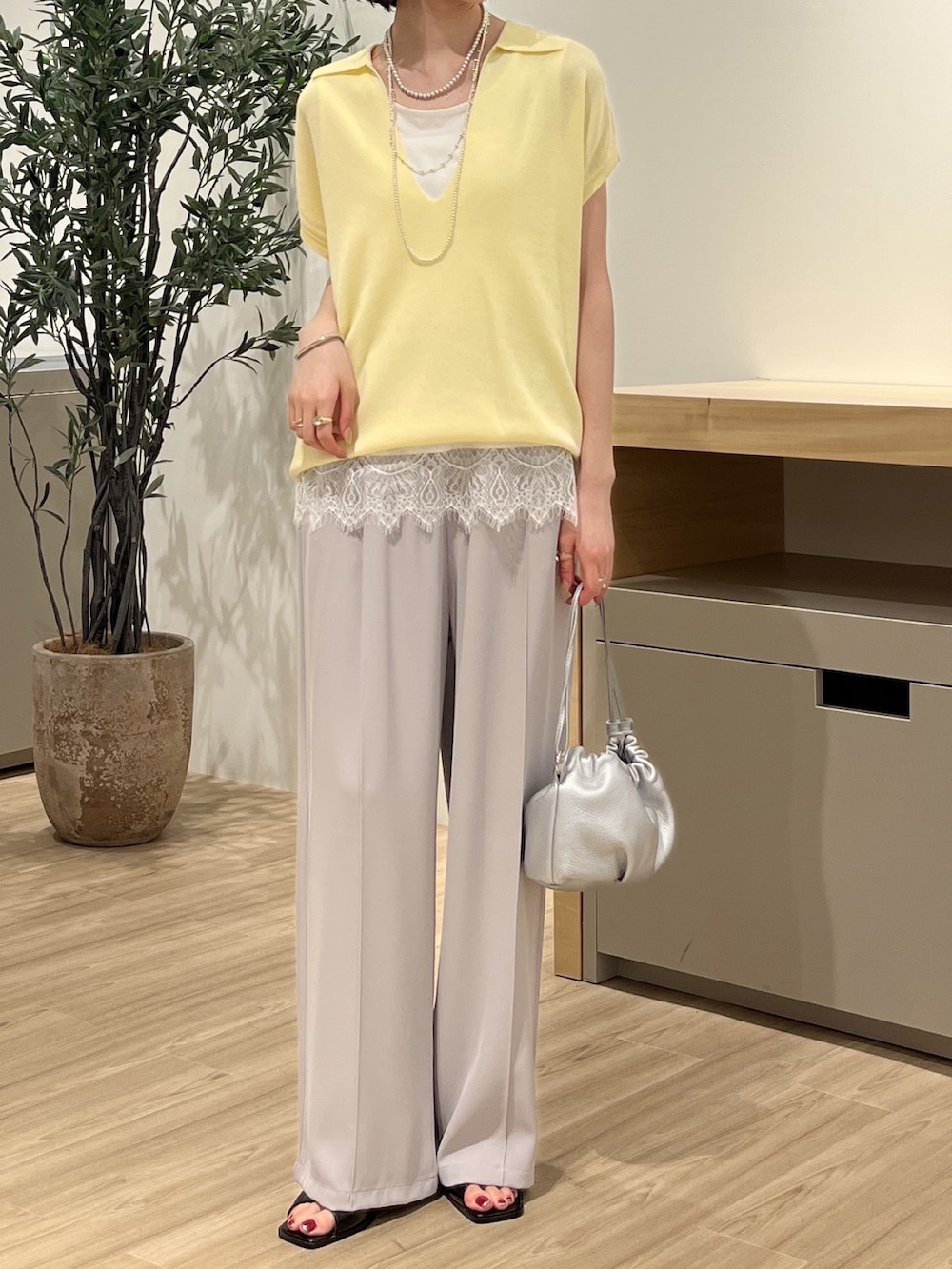 イエロー系のニット/セーター、ホワイト系のTシャツ/カットソー、シルバー系のトートバッグを着用したレディースの夏コーディネートの2枚目の写真