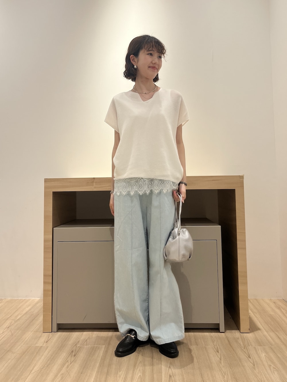 ホワイト系のニット/セーター、ブルー系のデニムパンツ、シルバー系のトートバッグを着用したレディースの夏コーディネートの3枚目の写真