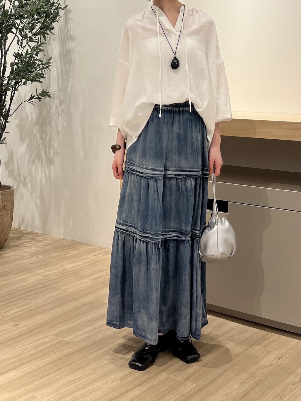 ホワイト系のシャツ/ブラウス、ブルー系のスカート、シルバー系のトートバッグを着用したレディースの夏コーディネートの2枚目の写真