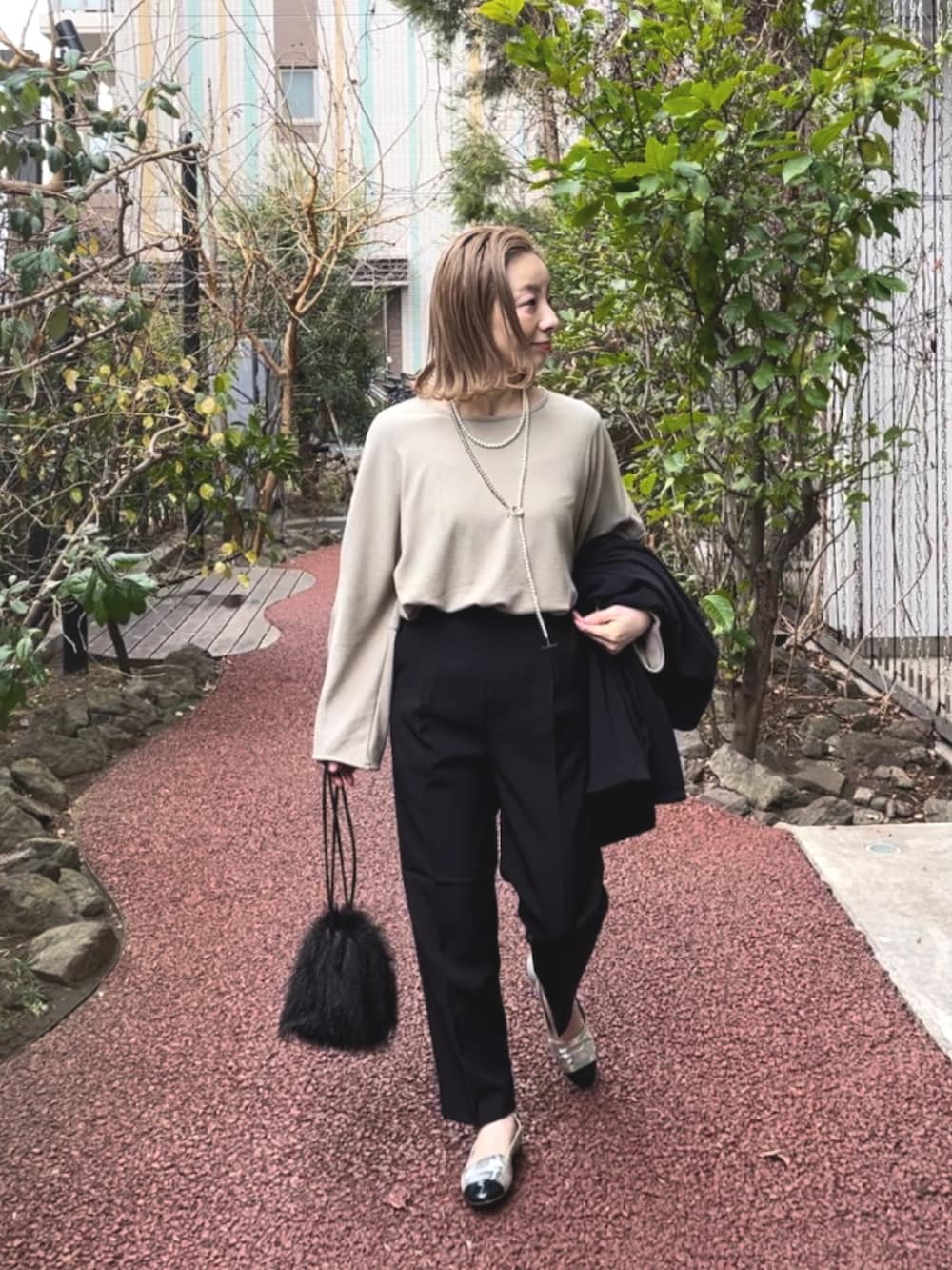 ブラック系のスラックス、ベージュ系のTシャツ/カットソー、ブラック系のテーラードジャケットを着用したレディースの冬コーディネートの4枚目の写真