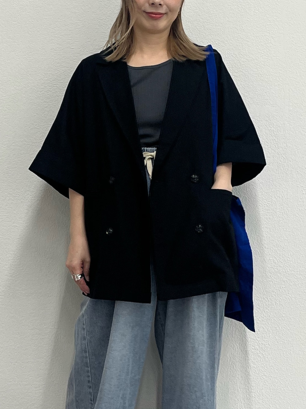 ブラック系のテーラードジャケット、ブルー系のデニムパンツ、ブラック系のサンダルを着用したレディースの夏コーディネートの4枚目の写真