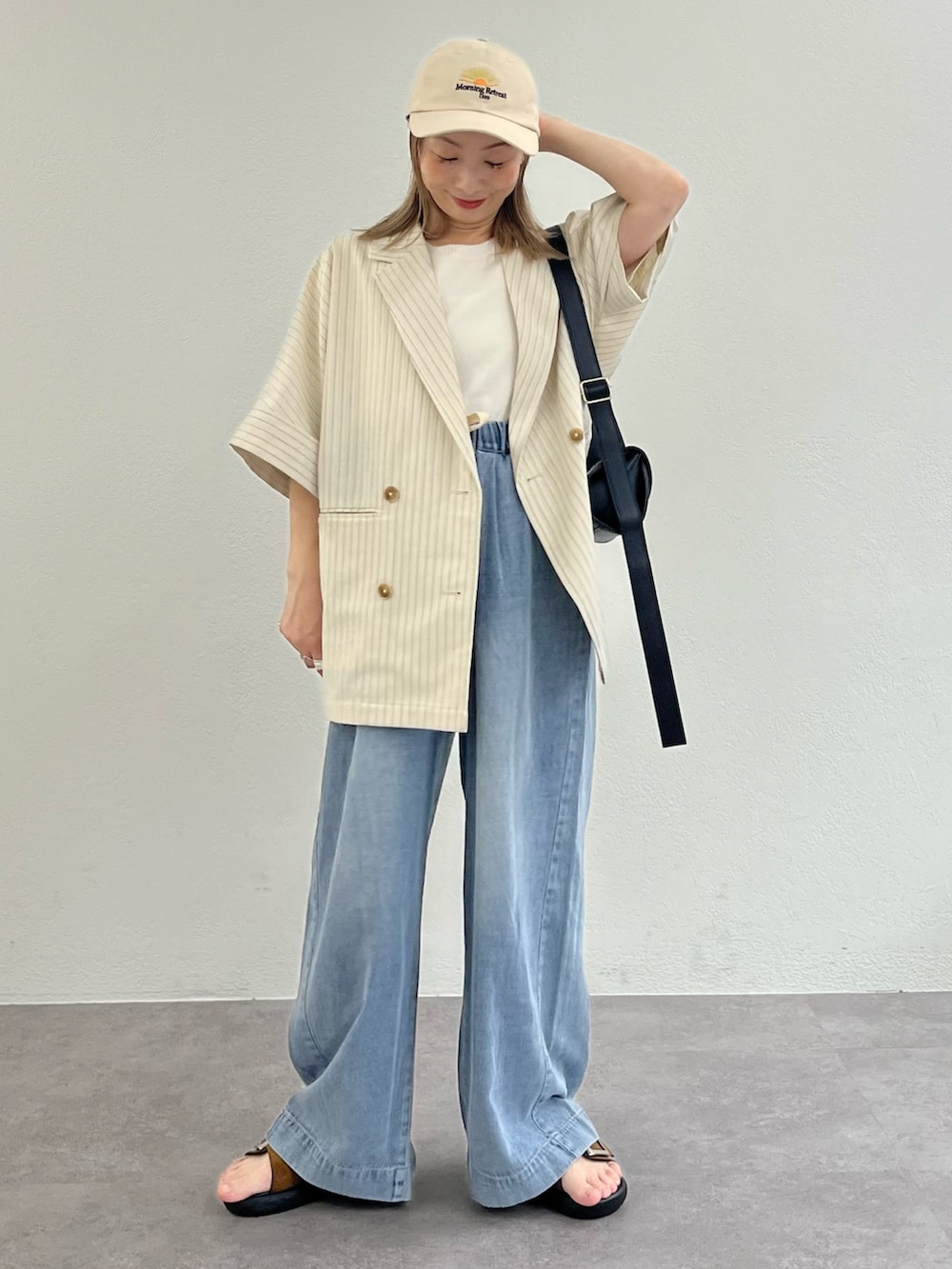 ブラウン系のサンダル、ブルー系のデニムパンツ、ホワイト系のテーラードジャケットを着用したレディースの夏コーディネートの2枚目の写真