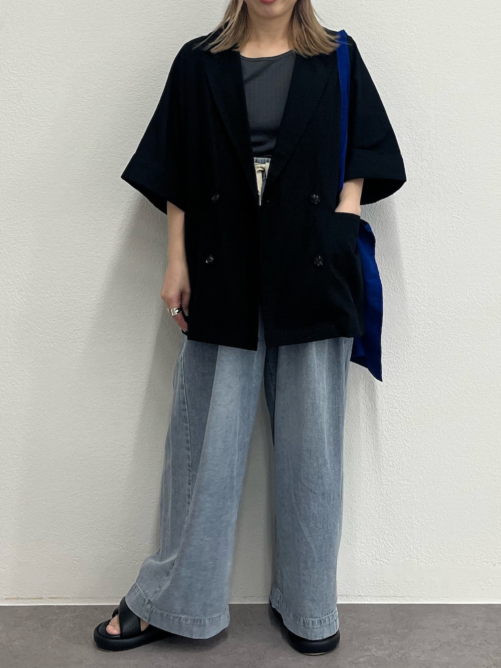 ブラック系のテーラードジャケット、ブルー系のデニムパンツ、ブラック系のサンダルを着用したレディースの夏コーディネートの3枚目の写真