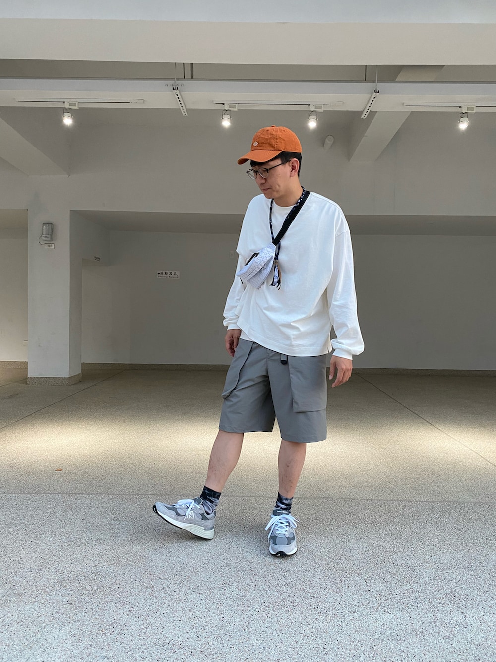 ホワイト系のトップス、ホワイト系のボディバッグ/ウエストポーチ、グレー系のパンツを着用したメンズの冬コーディネートの2枚目の写真