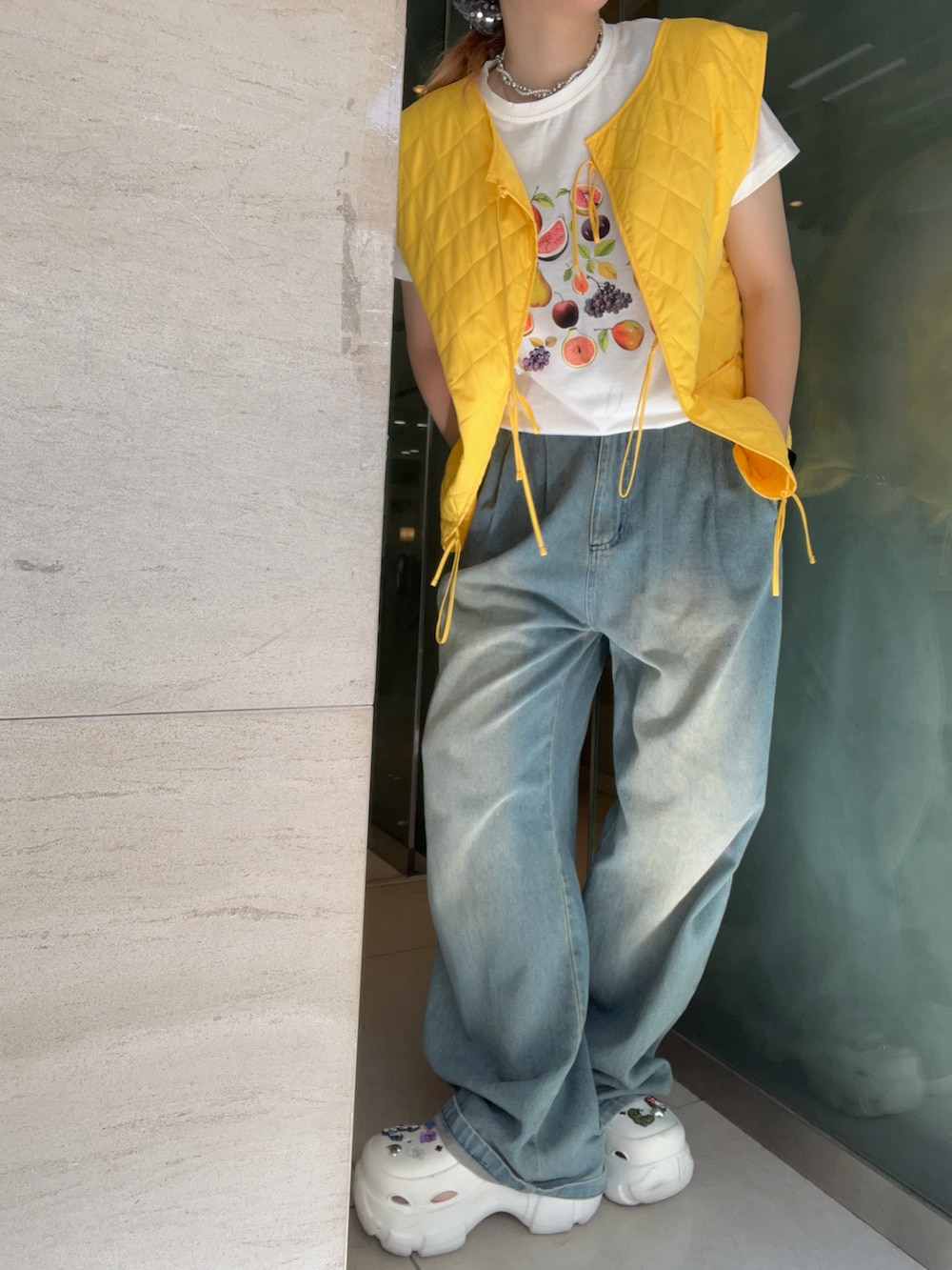 ブルー系のデニムパンツ、ホワイト系のサンダル、イエロー系のベストを着用したレディースの夏コーディネートの3枚目の写真