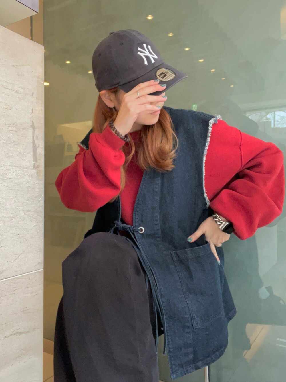 ブラック系のデニムパンツ、ブルー系のベスト、レッド系のニット/セーターを着用したレディースの冬コーディネートの2枚目の写真