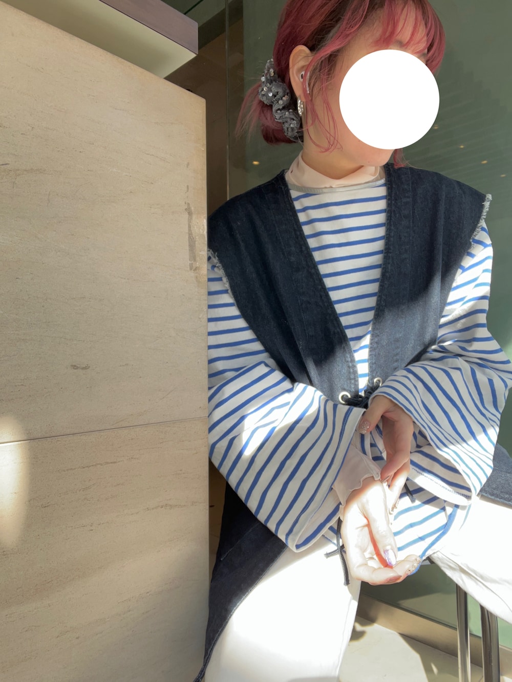 ホワイト系のデニムパンツ、ブルー系のスニーカー、ブルー系のベストを着用したレディースの春コーディネートの3枚目の写真